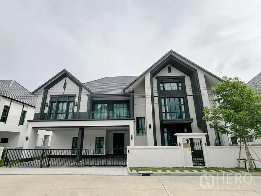 Detached House for rent or sale in Bang Phli, Samut Prakan - Modern two-storey detached house with gabled roof, large black-framed windows and a gated carport.