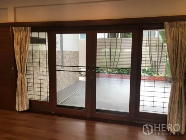 บ้าน ให้เช่าในWatthana, Bangkok - ประตูกระจกบานเลื่อนพร้อมผ้าม่าน เปิดสู่ระเบียงส่วนตัวและแปลงต้นไม้