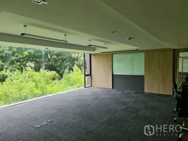 สำนักงาน ให้เช่าในWatthana, Bangkok - สำนักงานแบบเปิดโล่ง กระจกเต็มผืนรับวิวต้นไม้ พื้นพรม โคมไฟเส้นแขวน และผนังไม้พร้อมบอร์ดเขียนได้.
