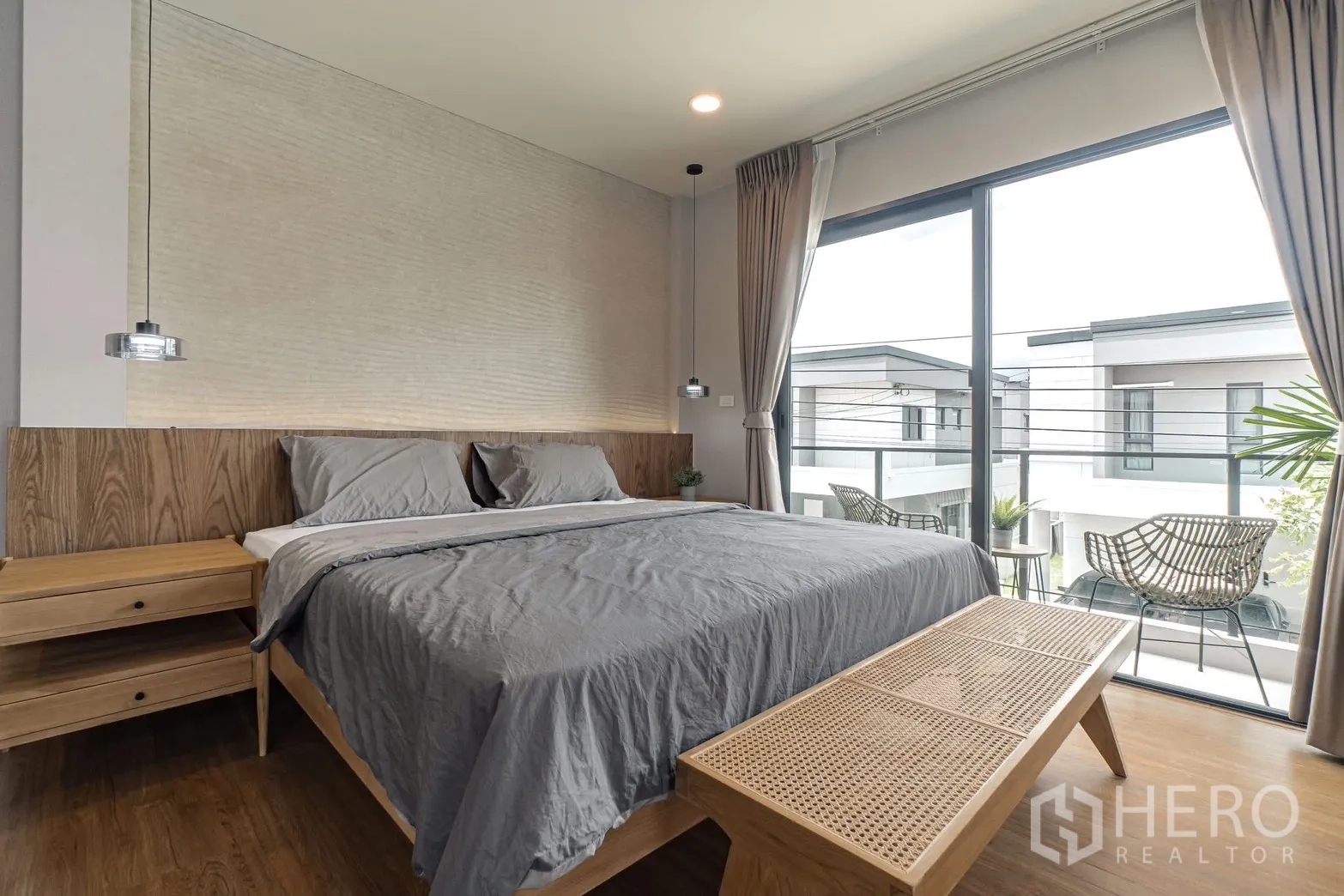 独栋房屋 for rent in Bang Phli, Samut Prakan - 主卧配吊灯、藤编长凳与阳台景观。