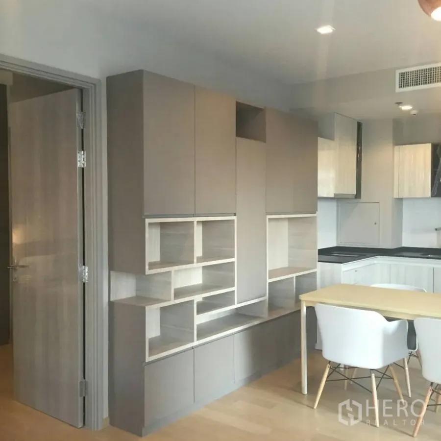 公寓 出租在Watthana, Bangkok - 现代公寓内置收纳墙，旁设小餐桌与L形厨房，木地板温暖简洁。