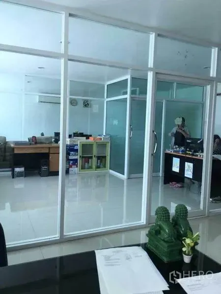 Factory for rent or sale in Samut Prakan - Open-plan office with glass partitions, air-conditioning and desks inside the administrative area.