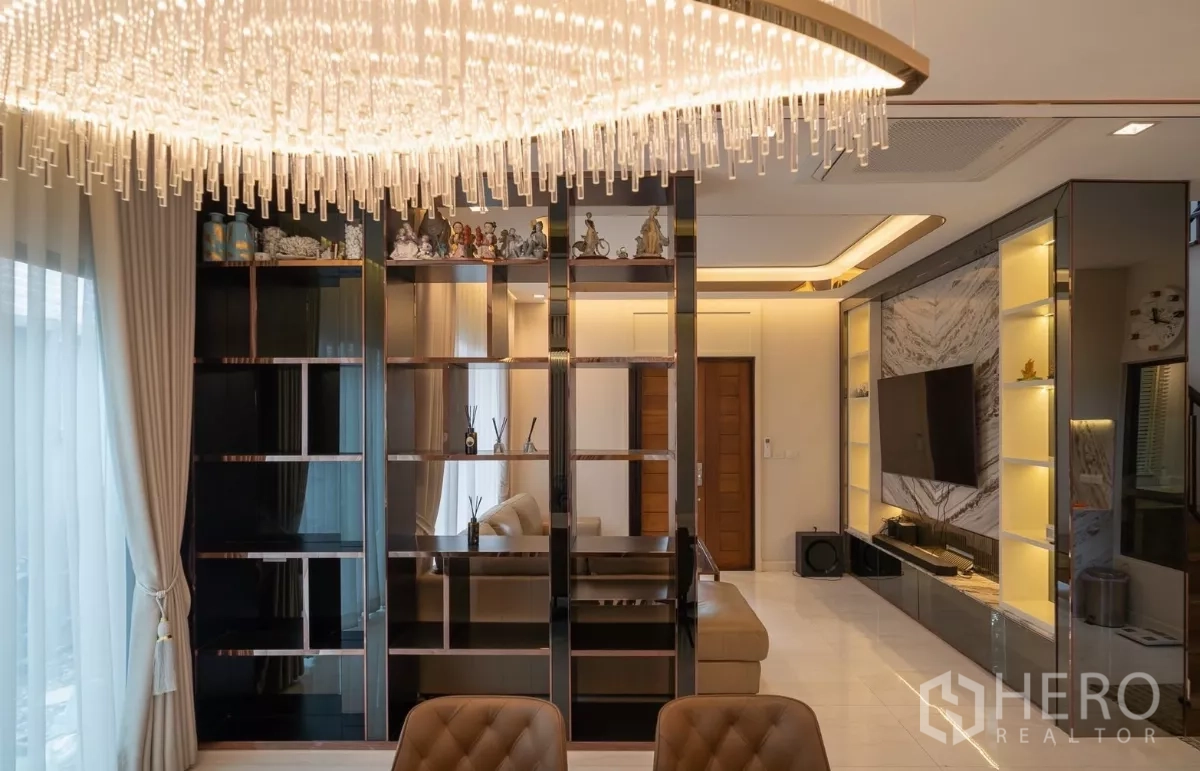 Detached House for rent or sale in Saphan Sung, Bangkok - Lounge view with glossy shelving partition and crystal chandelier.