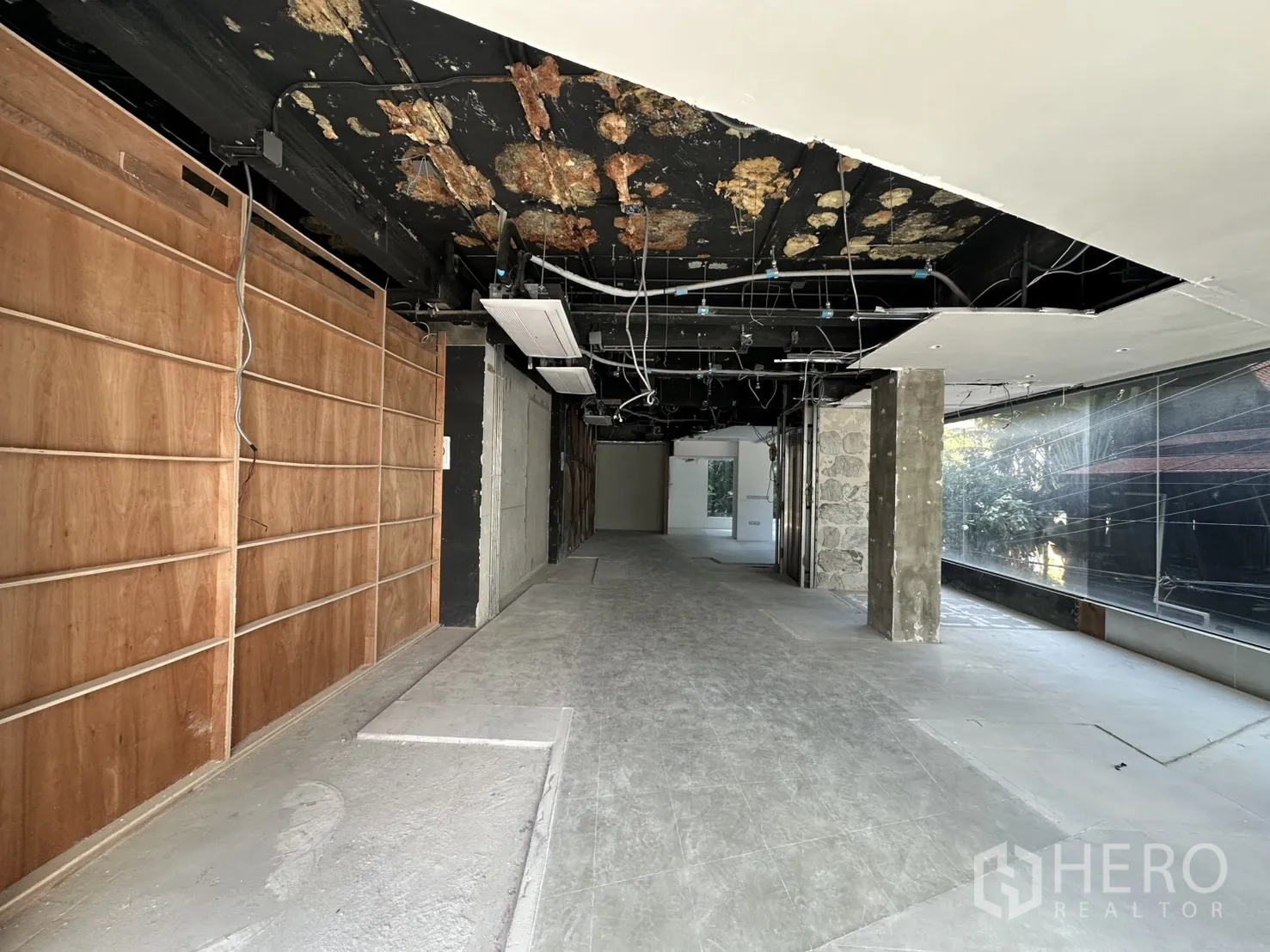 พื้นที่ขายของ for rent in Watthana, Bangkok - พื้นที่ขนาดใหญ่กำลังปรับปรุง เพดานสีดำเปิดงานระบบ และกระจกยาวด้านข้าง.