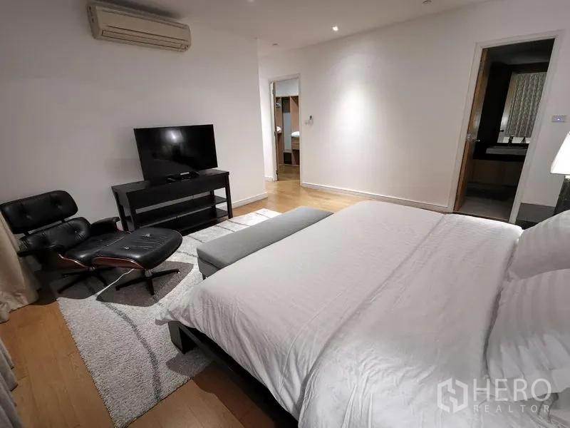 คอนโด ให้เช่าในWatthana, Bangkok - มุมห้องนอนหลักพร้อมชั้นวางทีวี ทางเข้าห้องน้ำในตัว และเก้าอี้เลานจ์สไตล์อีมส์