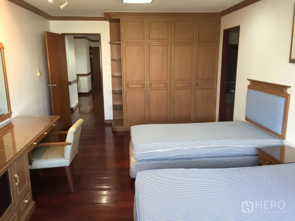 公寓 出租在Watthana, Bangkok - 明亮的双床卧室，配书桌、大量衣柜与亮泽木地板。