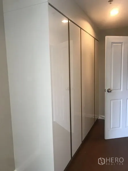 Condominium for rent or sale in Huai Khwang, Bangkok - Hallway with sleek built-in wardrobes and a white door in a contemporary condo.
