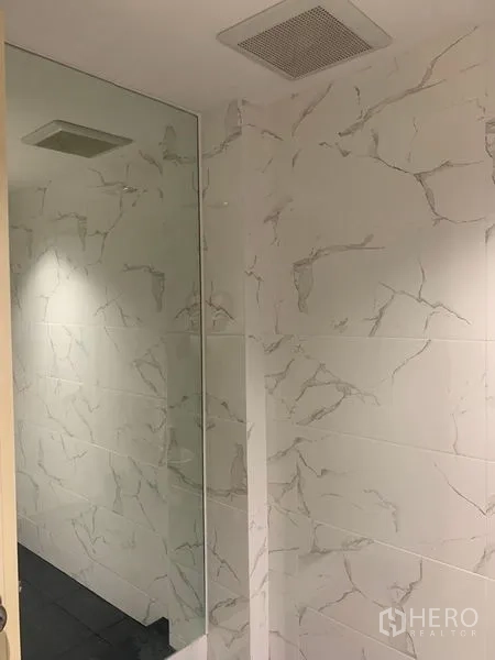 Townhouse for rent in Din Daeng, Bangkok - Shower area with marble-effect tiles and a glass partition in a modern bathroom.