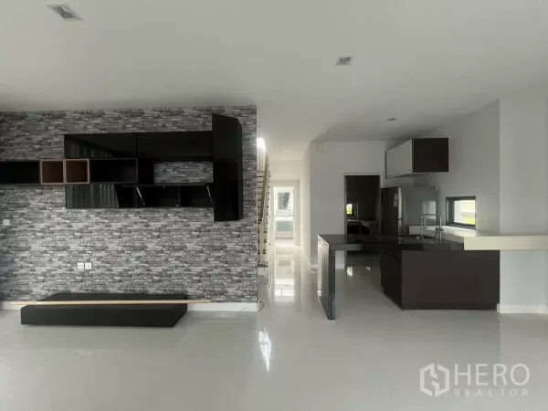Detached House for sale in Bang Kapi, Bangkok - Open-plan living and dining area with stone feature wall and built-in shelving beside the kitchen.