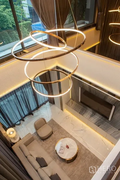 บ้าน ให้เช่าหรือขายในBangkok - มุมมองจากชั้นบนเห็นห้องนั่งเล่นเพดานสูงและโคมไฟวงแหวน
