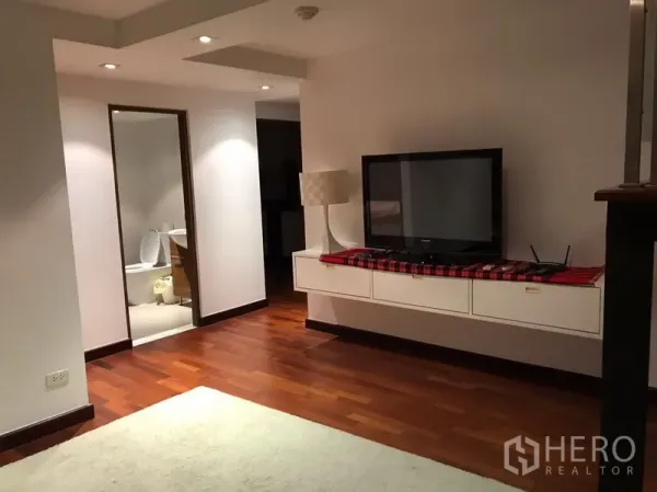 Condominium for rent in Watthana, Bangkok - TV wall with floating cabinet, recessed lighting and a doorway to the bathroom.
