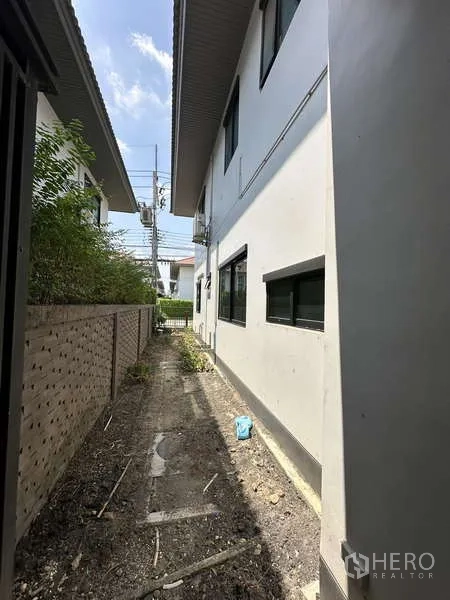 Detached House for sale in Lam Luk Ka, Pathum Thani - Narrow service path between the house and boundary wall with windows.