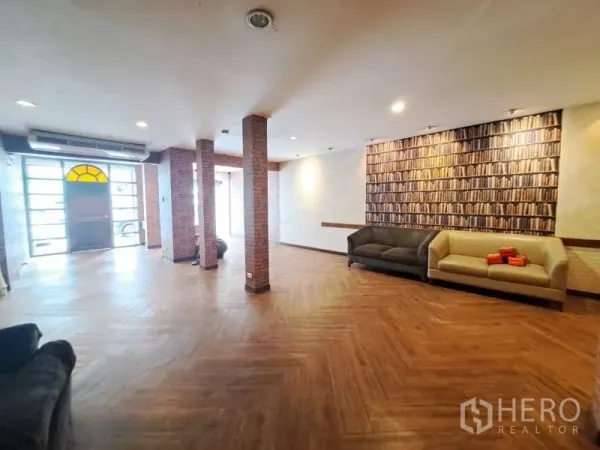 Shophouse for rent in Watthana, Bangkok - Spacious hall with herringbone wood floor, brick columns and sofas.