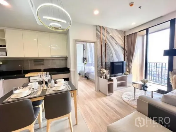 Condominium for rent in Khlong Toei, Bangkok - Open-plan kitchen, dining and living area with modern pendant lights and balcony access.