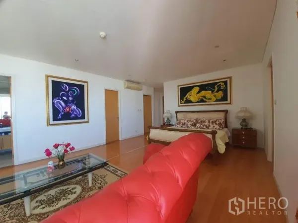 公寓 出售在Watthana, Bangkok - 宽敞卧室套间，红色纽扣沙发、玻璃茶几、装饰画与木地板。