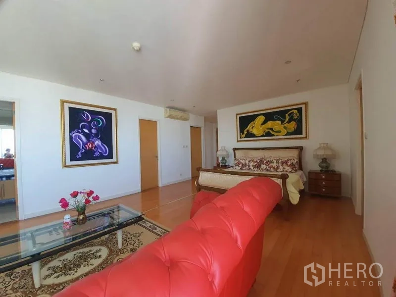 公寓 出售在Watthana, Bangkok - 宽敞卧室套间，红色纽扣沙发、玻璃茶几、装饰画与木地板。