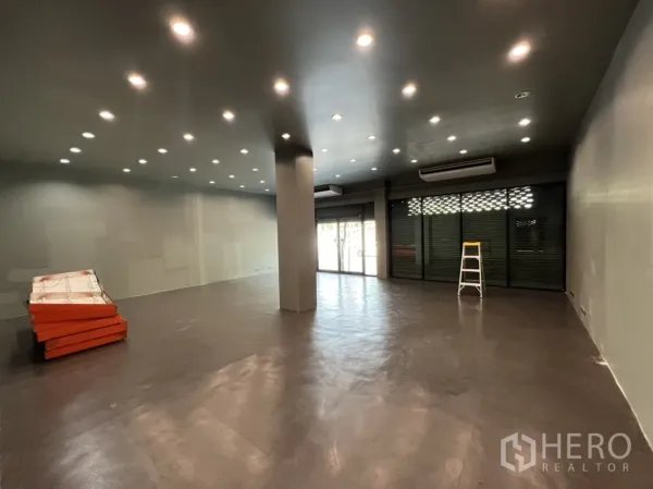 Shophouse for rent in Phra Khanong, Bangkok - Open-plan shop space with spotlight ceiling, large glass frontage with roller shutters and air-conditioning units.