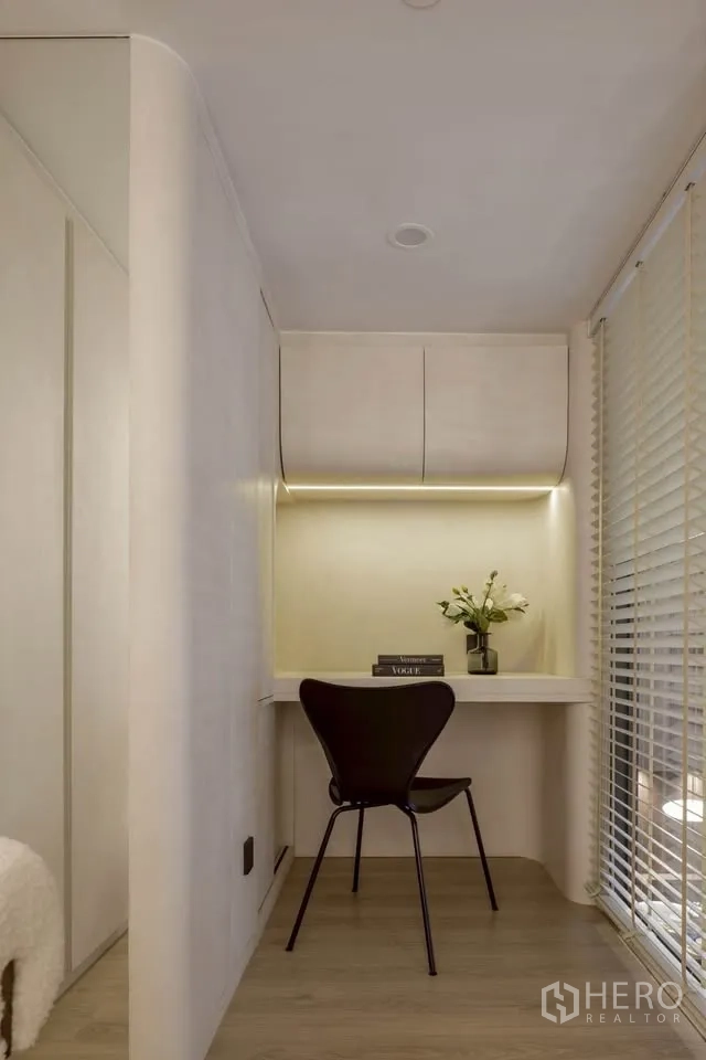 Condominium for rent in Khlong Toei, Bangkok - Small work nook with built-in desk, chair, overhead cabinets, and blinds.