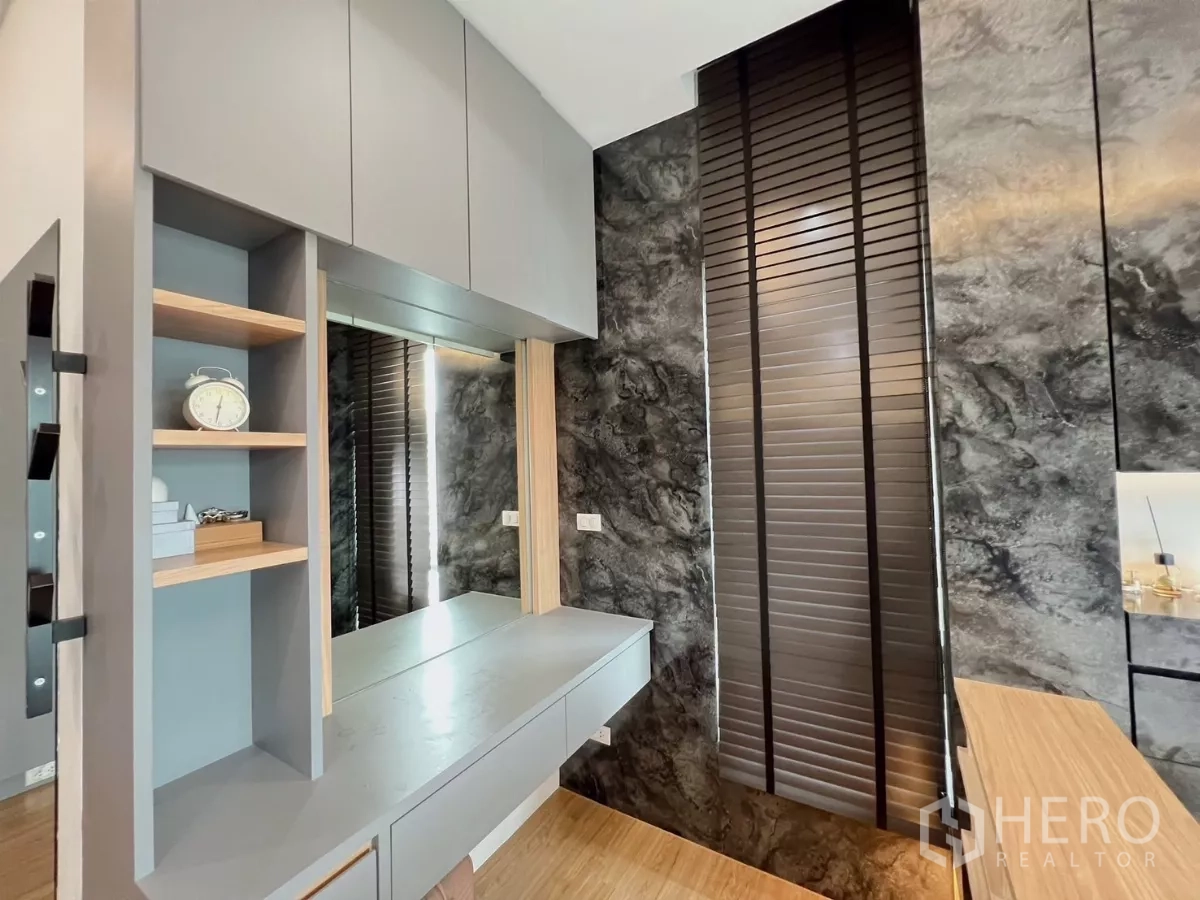 Detached House for rent or sale in Khlong Luang, Pathum Thani - Bedroom vanity area with grey cabinetry and dark slatted blinds.