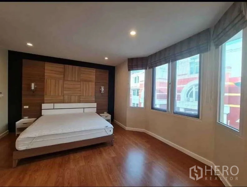 Townhouse for rent in Phra Khanong, Bangkok - Corner master bedroom with large windows, feature wood panel headboard and warm floors.