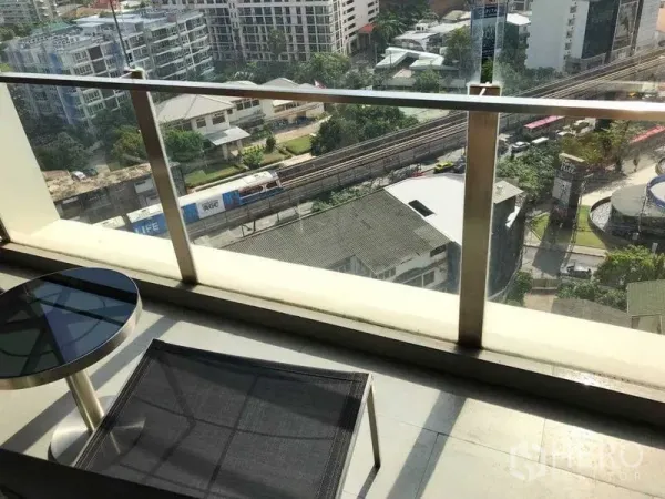 Condominium for rent in Watthana, Bangkok - Private balcony with glass railing, outdoor table and chair overlooking city skyline and the BTS Thonglor track.