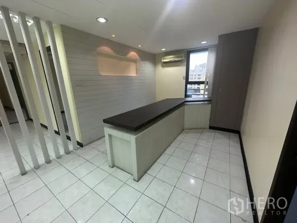 Office Space for rent in Bang Rak, Bangkok - Reception-style area with built-in counter, tiled floors, accent wall and a window air conditioner.
