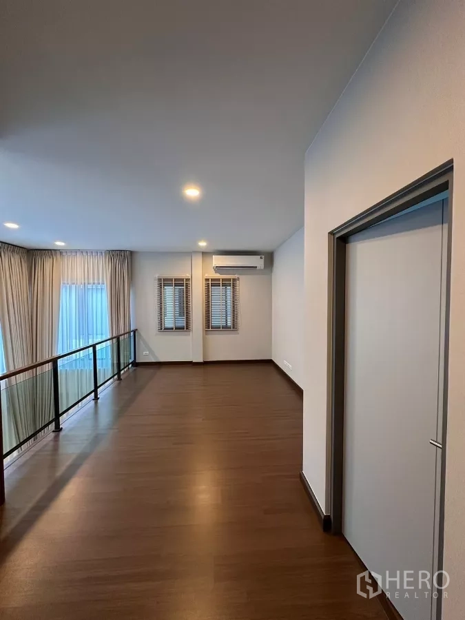 独立式住宅 出租在Bang Phli, Samut Prakan - 二层走廊，木地板、窗户与空调。