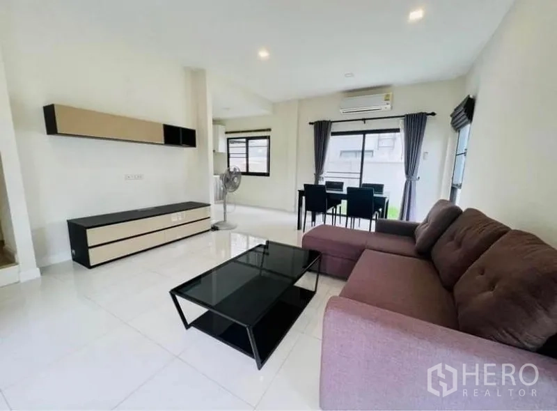 Townhouse for rent in Saphan Sung, Bangkok - Open-plan lounge and dining space with glossy tile floors, curtains, air conditioning and ample windows.