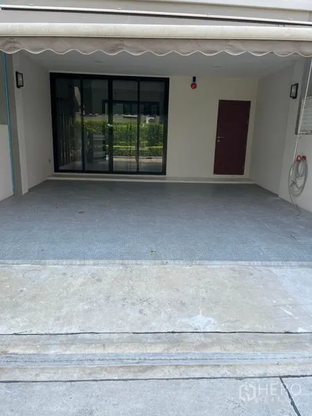 Townhouse for rent or sale in Yan Nawa, Bangkok - Wide two-car parking bay under awning with black-framed sliding doors.