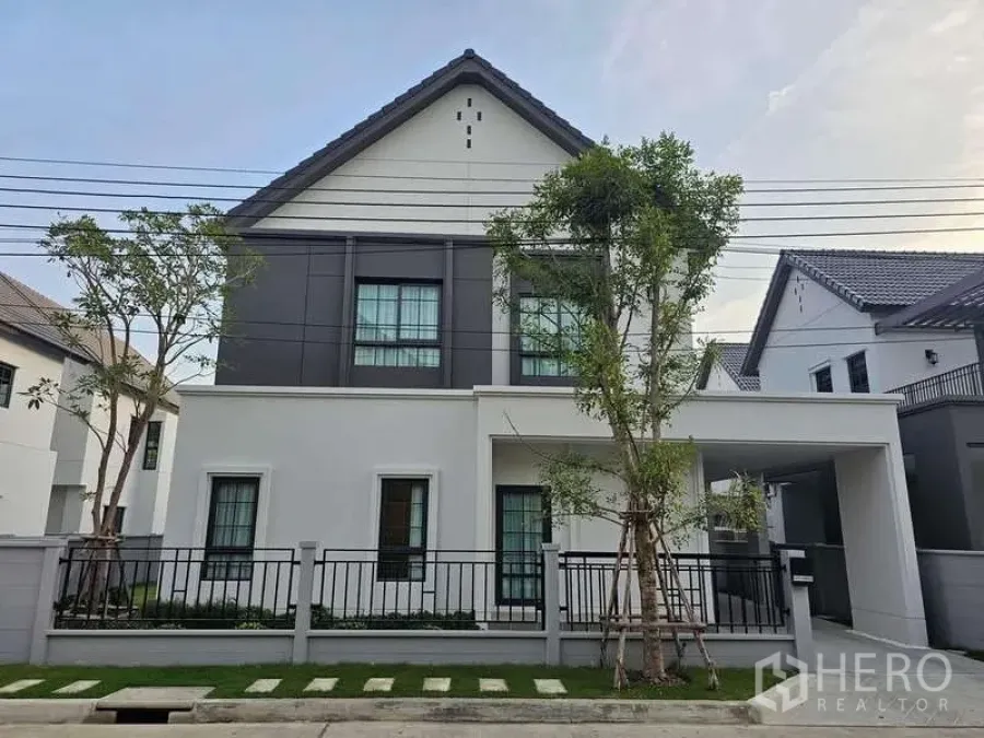 Detached House for rent in Bang Phli, Samut Prakan - Street-side view of a white-and-grey detached home with fenced garden and driveway.
