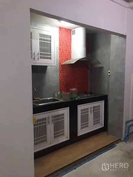 独立式住宅 出租在Din Daeng, Bangkok - 紧凑型橱柜厨房，带水槽、灶台、抽油烟机和红色马赛克防溅板。