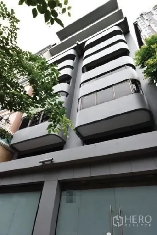 店屋 出租在Watthana, Bangkok - 现代多层店屋外立面，弧形阳台与街树。