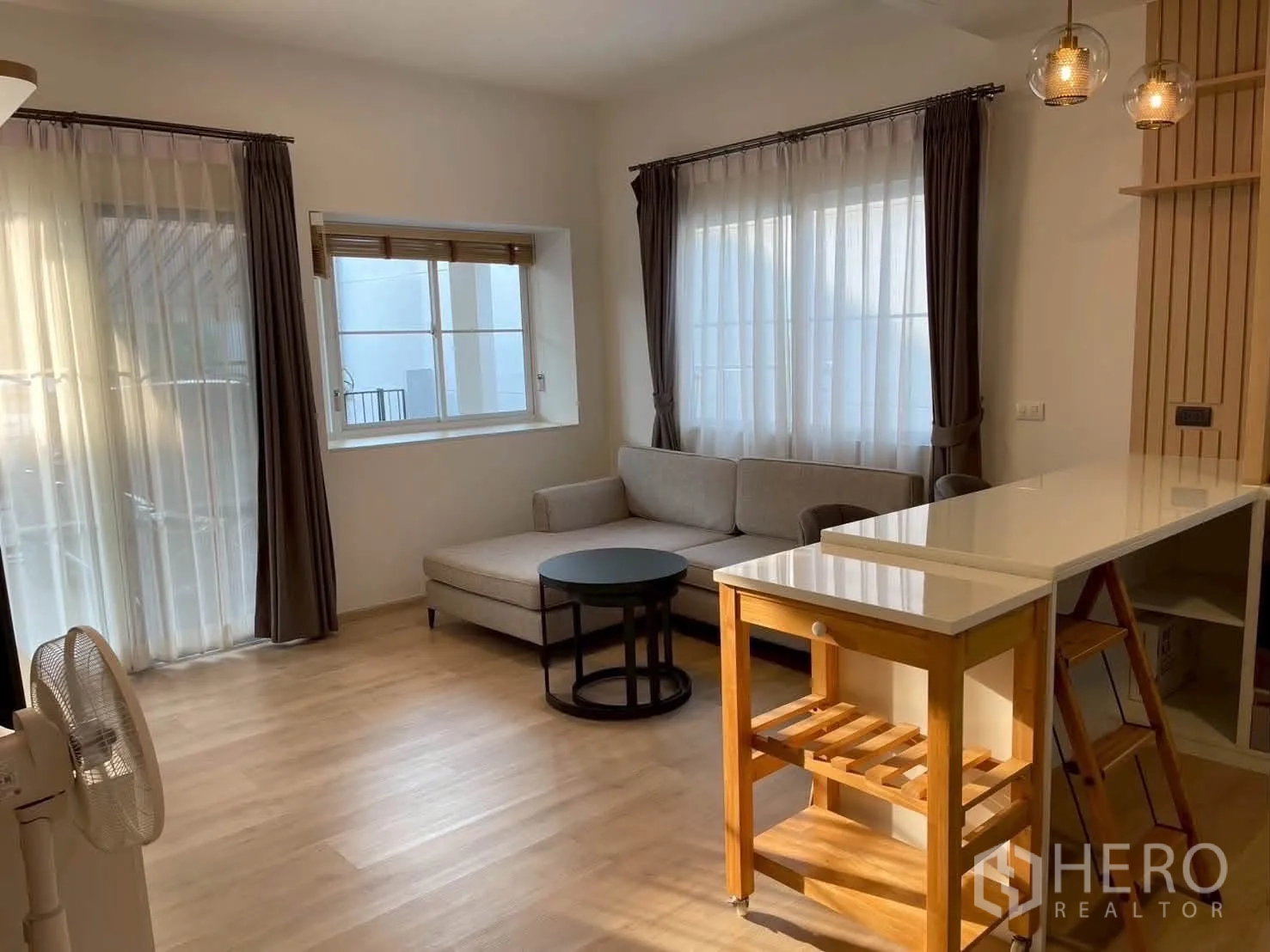 Townhouse for rent in Bang Phli, Samut Prakan - Open-plan living with L-shaped sofa next to peninsula counter.