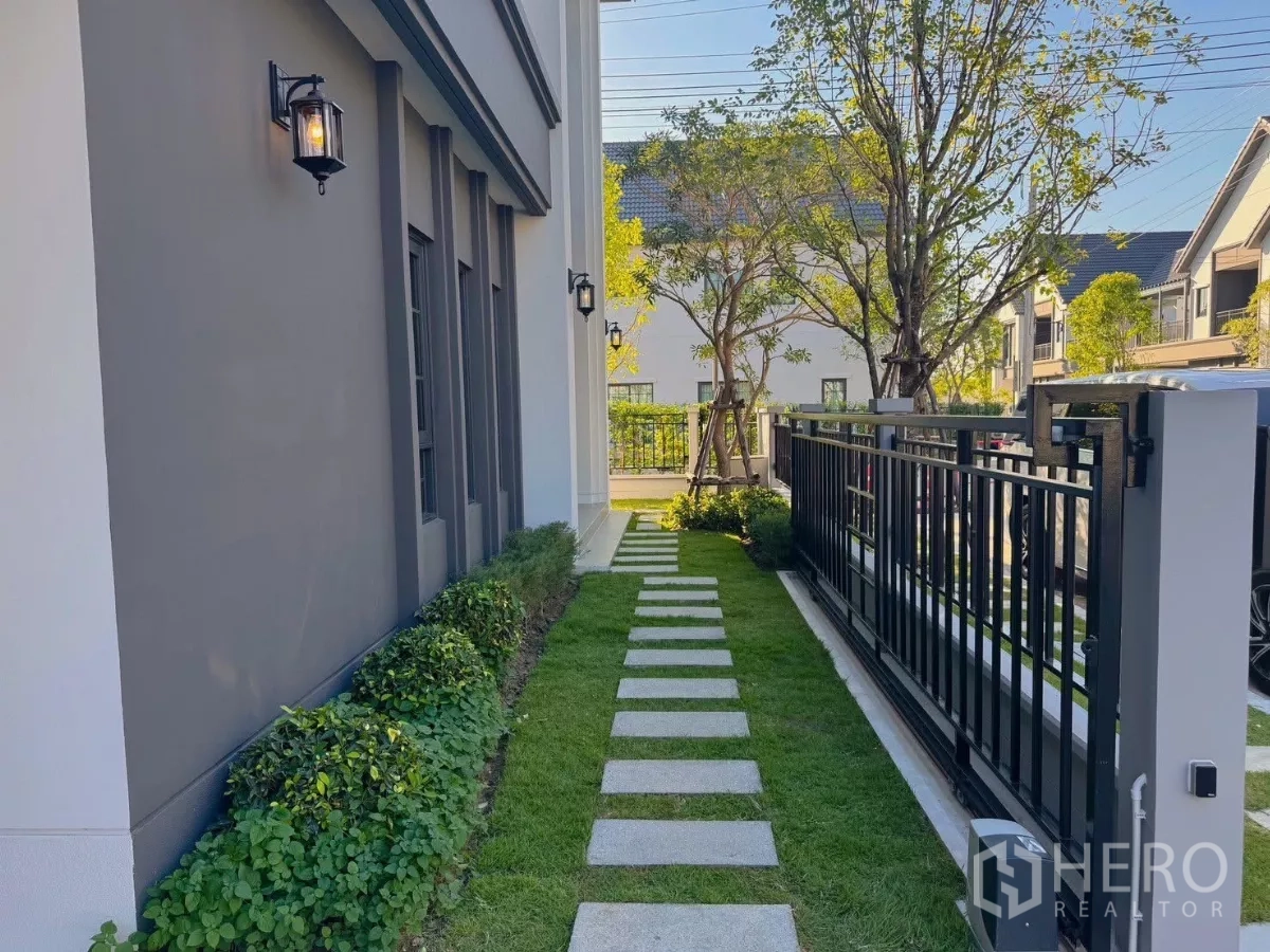 Detached House for rent or sale in Bang Phli, Samut Prakan - Side garden with stepping-stone path, lawn and black metal fence.