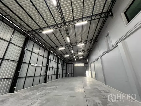 Warehouse for rent in Yan Nawa, Bangkok - Long warehouse bay with metal cladding walls and a roller shutter door at the far end.