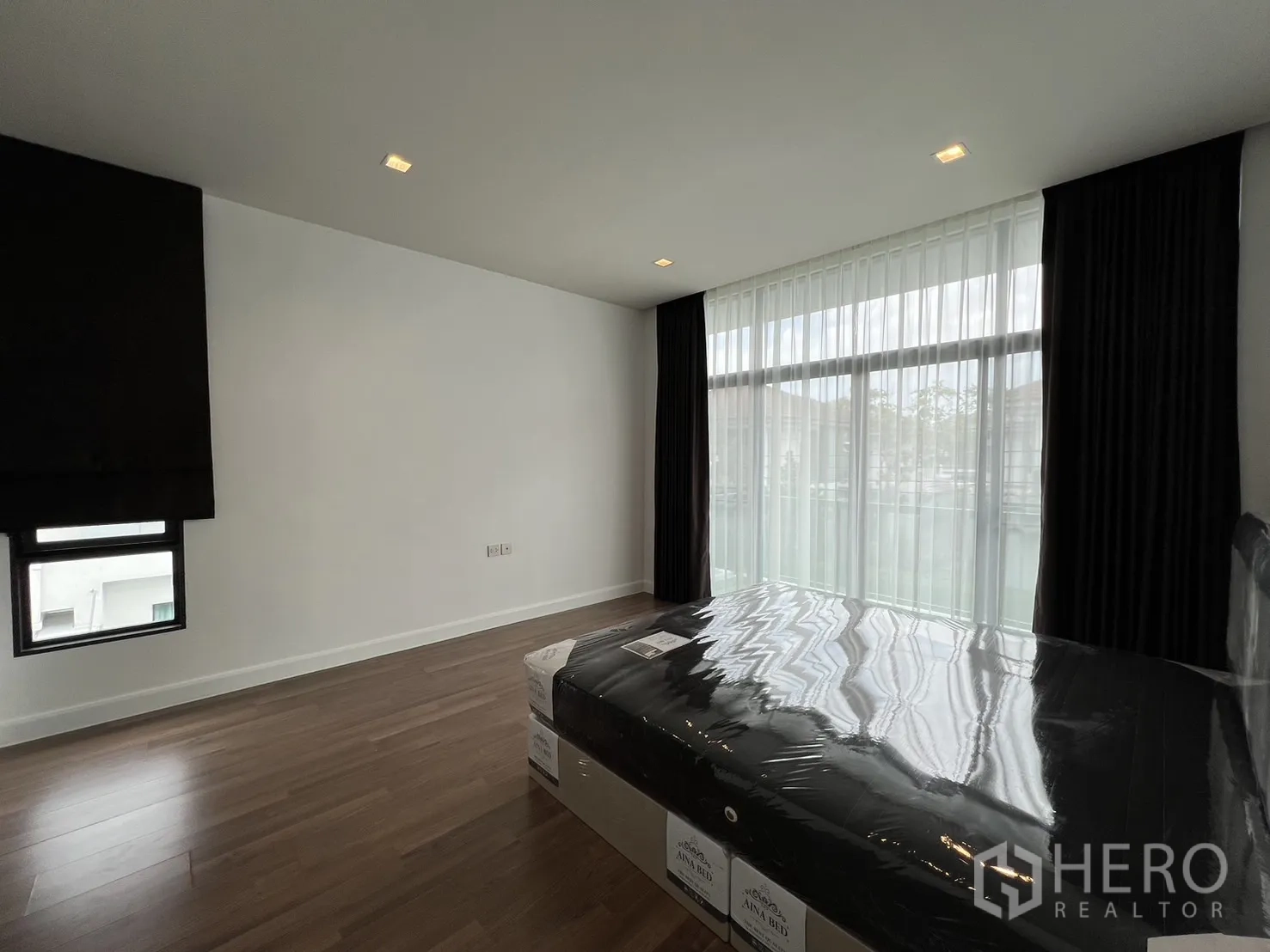 Detached House for rent in Bang Kapi, Bangkok - Master bedroom angle showing balcony windows and timber flooring.