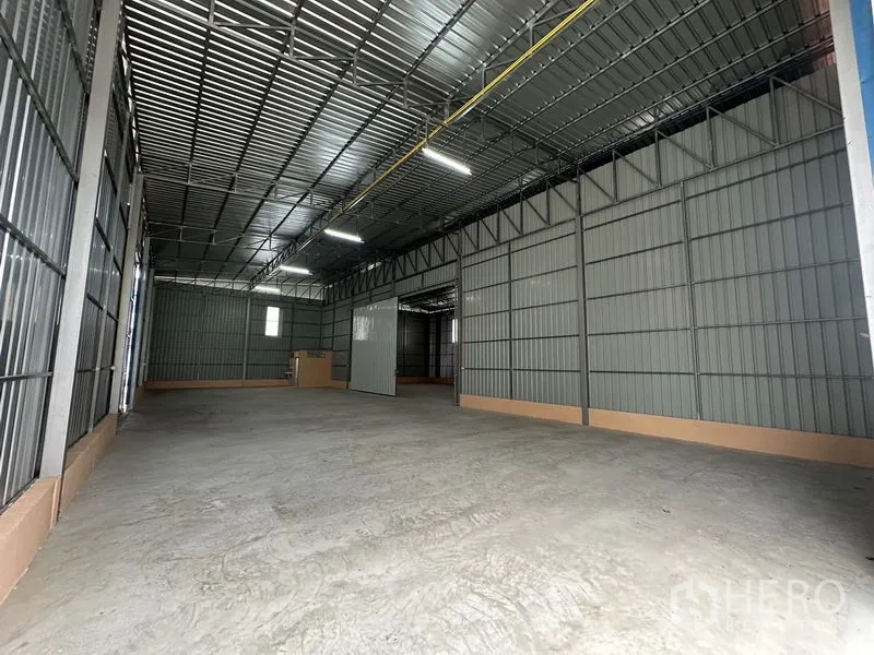 Warehouse for rent in Bueng Kum, Bangkok - Open-plan warehouse hall with partition doorway connecting to rear storage bay.