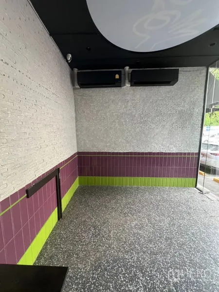 Retail Space for rent in Watthana, Bangkok - Compact interior with terrazzo floor, white brick wall, purple and green tiles, and ceiling AC units.