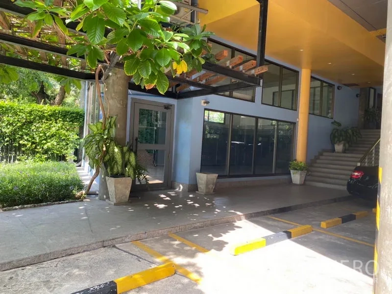零售空间 出租在Watthana, Bangkok - 店外有顶车道与停车位，绿荫与雨棚覆盖。