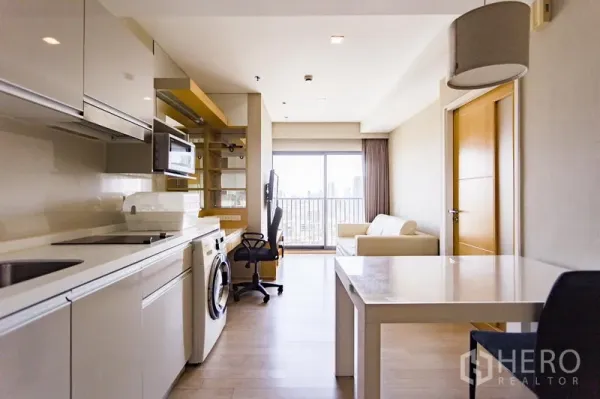 Condominium for rent in Khlong Toei, Bangkok - Bright living-dining space with balcony city view, white dining table, sofa and built-in kitchen with washer at Noble Remix.
