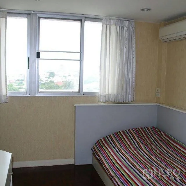 公寓 出租在Watthana, Bangkok - 角落卧室，条纹床品，大窗与空调，享城市景观。