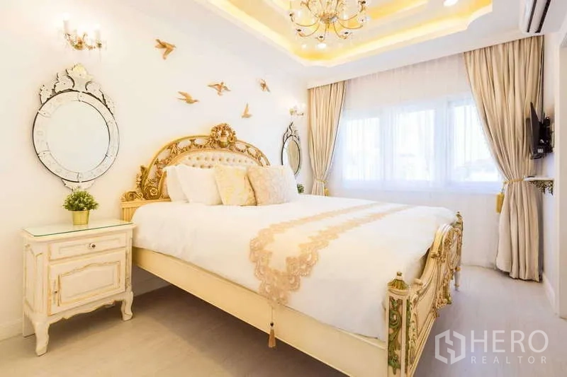 Townhouse for rent in Lat Phrao, Bangkok - Bright bedroom with gold accents, chandelier and large windows.
