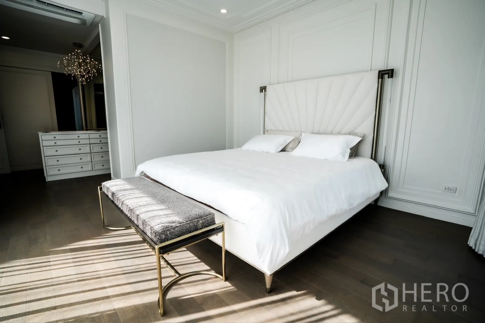 Detached House for rent or sale in Bang Kapi, Bangkok - Sunlit master bedroom with padded headboard, bench seat and warm wood flooring.