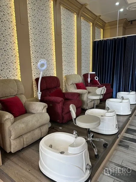 Retail Space for rent in Khlong Toei, Bangkok - Close view of reclining pedicure chairs with stools, white basins, and a curtain divider in a salon.