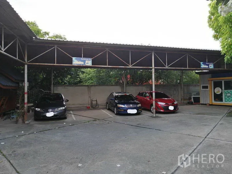 办公空间 出租在Bueng Kum, Bangkok - 带顶棚的停车位，多辆车停在金属雨棚下。
