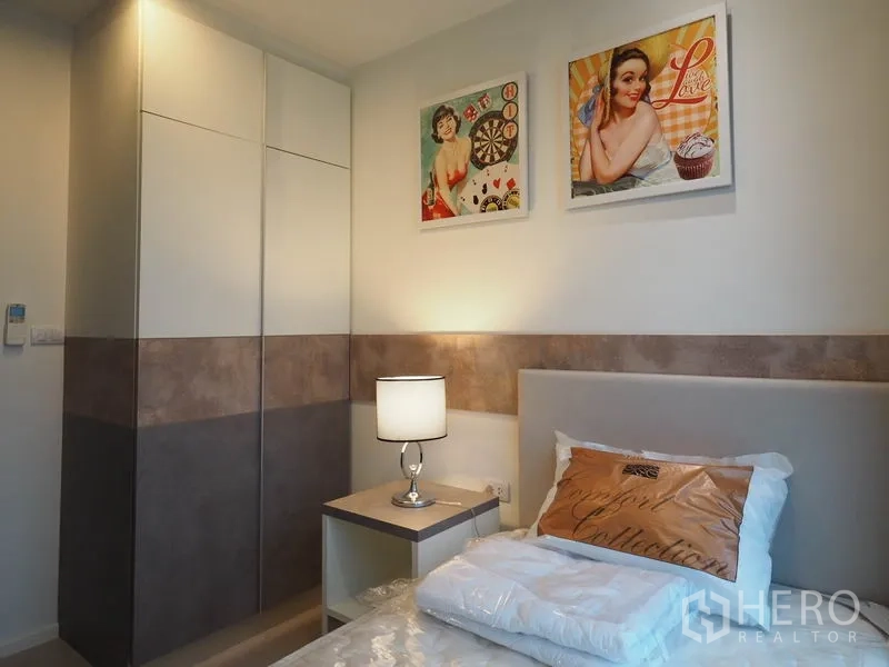 公寓 出租在Sathon, Bangkok - 卧室配内置衣柜、床头柜与墙面装饰画。