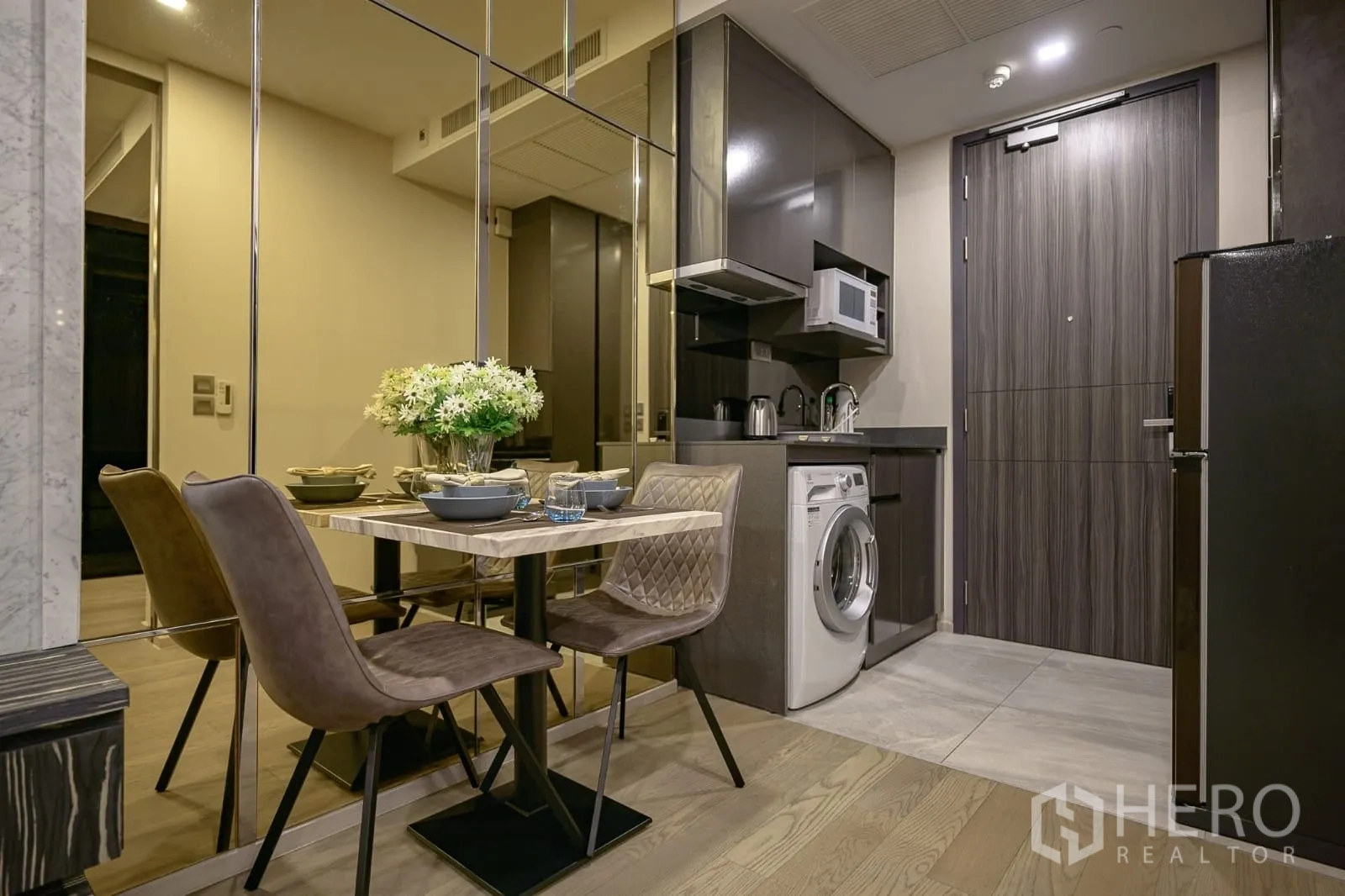 Condominium for rent in Watthana, Bangkok - Compact kitchenette with cabinets, microwave, washer and a dining set.