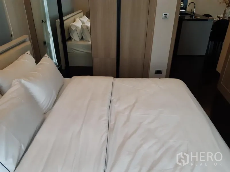 Condominium for rent in Watthana, Bangkok - Bedroom with bed, wardrobe and full-length mirror near the doorway.