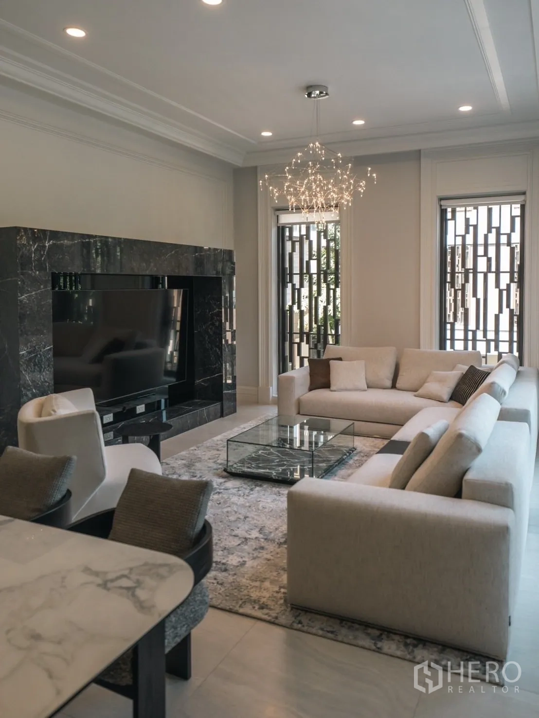 Detached House for rent or sale in Bang Kapi, Bangkok - Living room with neutral sectional sofas, glass coffee table and feature chandelier.