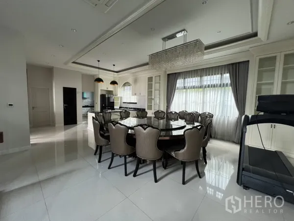 Detached House for rent or sale in Prawet, Bangkok - Spacious dining area with crystal chandelier beside a modern island kitchen.